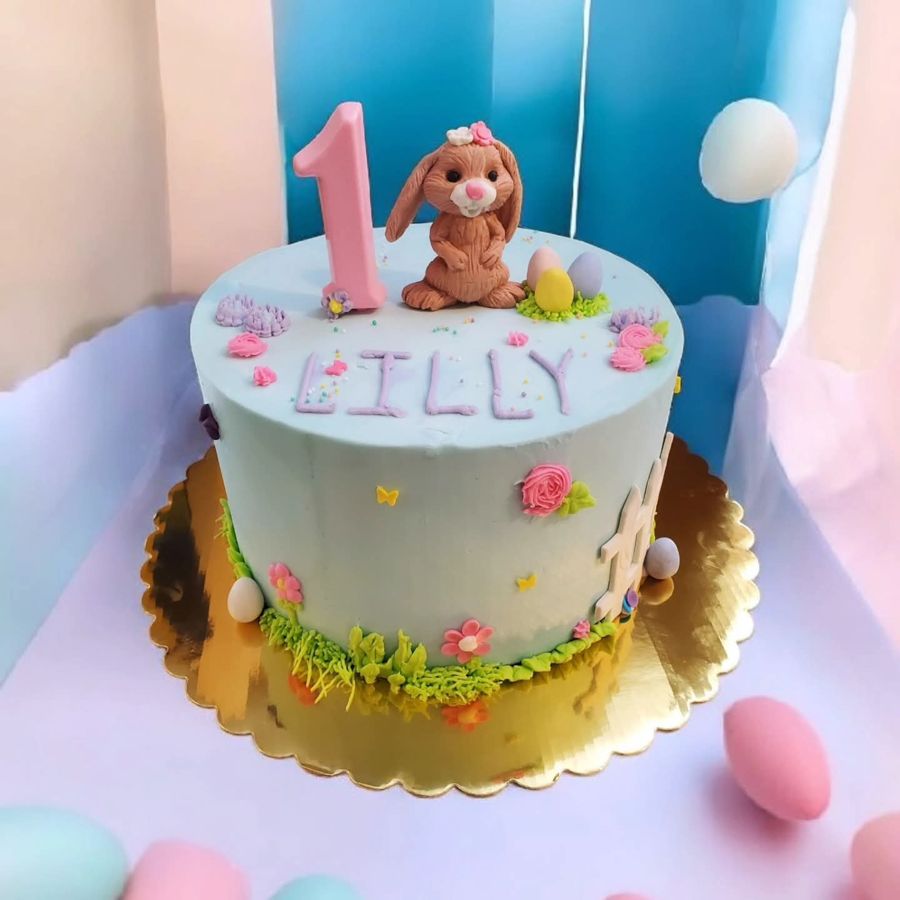 Pastel blue first birthday cake with a bunny, Easter eggs and piped flowers