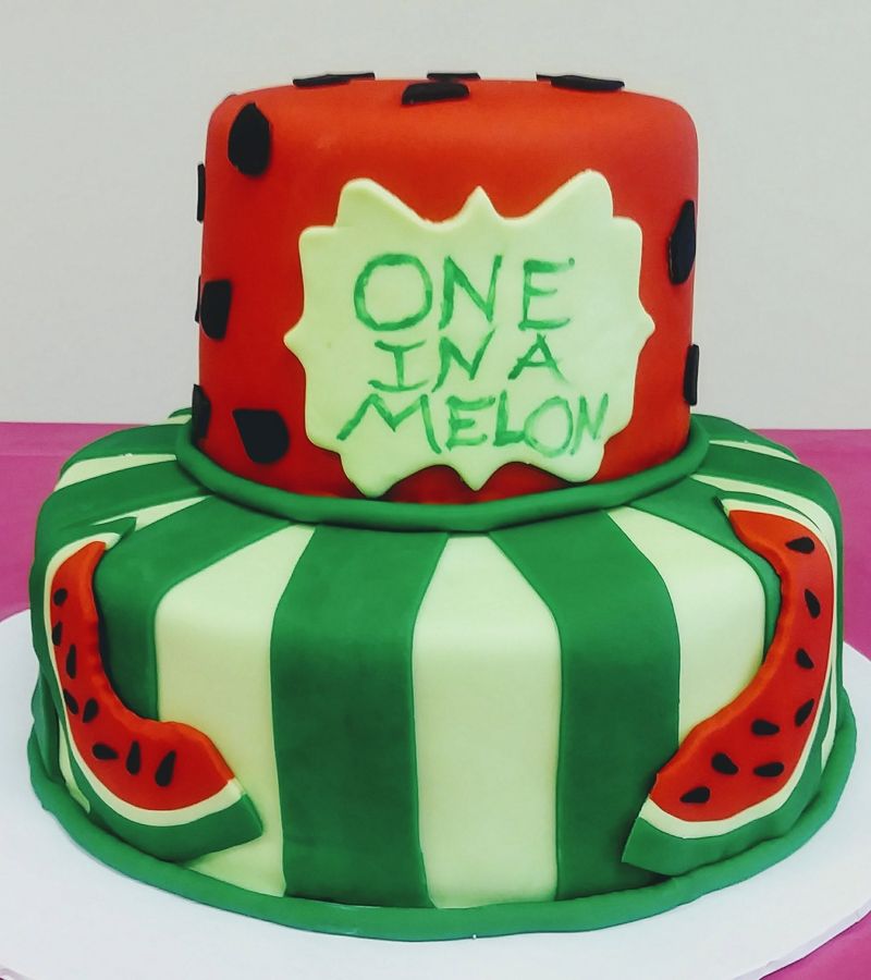 Two-tier watermelon first birthday cake reading One in a Melon