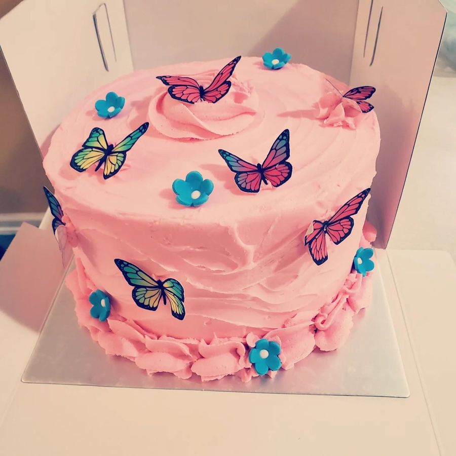 Pink buttercream cake with colorful butterflies and blue flowers