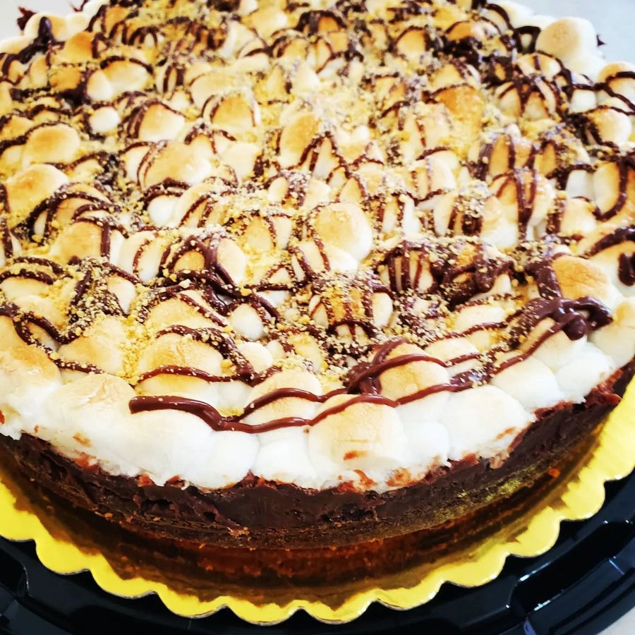 Brownie cake topped with toasted marshmallows, graham crumbs and chocolate drizzle